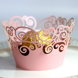 Pink laser-cut cupcake wrappers with elegant swirl hollow pattern for dessert display