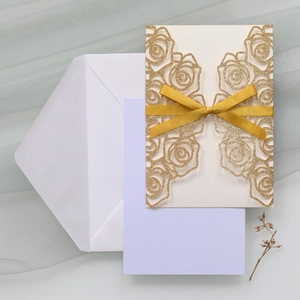 Detail of laser-cut gold glitter rose invitation with yellow ribbon and purple insert card