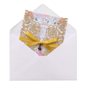 Detail of glitter laser cut rose wedding invitation with gold ribbon and floral insert