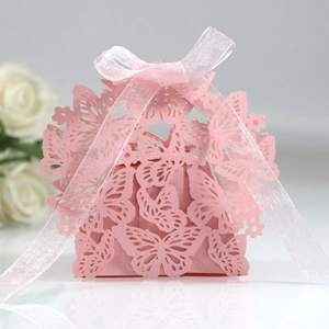 Pink laser-cut butterfly wedding favor box with a soft pink ribbon on a light surface