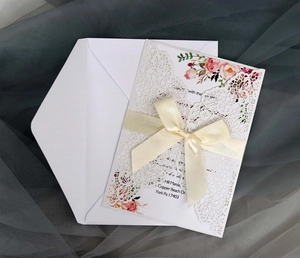 Detail of laser-cut lace invitation with silk bow and floral insert on mesh