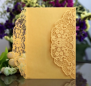 Close-up of laser-cut floral patterns on pearlescent gold wedding invitation card