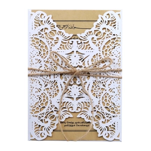 Close-up of laser-cut lace invitation with kraft paper and rustic twine bow detail