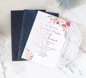 Detail of laser-cut lace invitation covers in navy, mist blue and white floral designs