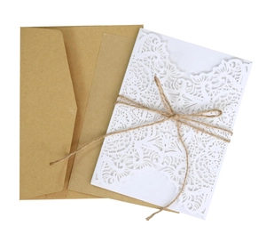 Close-up of laser-cut lace wedding invitation with kraft paper and rustic twine