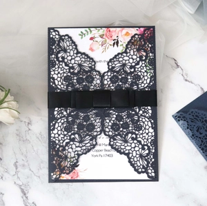Close-up of laser-cut wedding invitation with blue lace pattern and satin ribbon bow