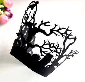 Macro shot of laser-cut black Halloween cupcake wrapper featuring RIP tombstones and trees