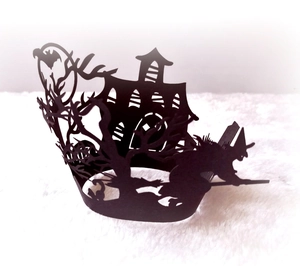 Detailed macro view of laser-cut Halloween cupcake wrapper featuring a black witch and castle