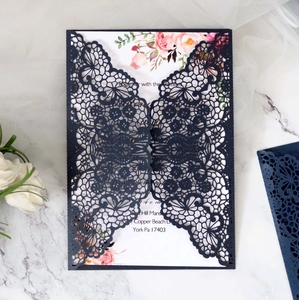 Close-up of laser-cut navy blue floral invitation sleeve and white floral inner card