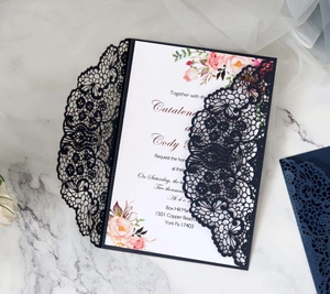 Detail of laser cut lace wedding invitation with floral print on elegant marble surface