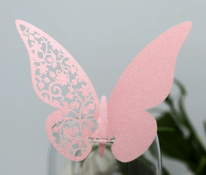 Close-up of pink laser-cut butterfly place card with glitter texture for wedding glasses
