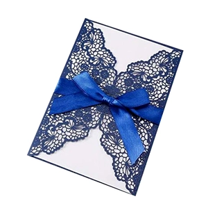 Detail showing the dark blue laser-cut lace floral pattern on a wedding invitation