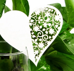 Macro detail of laser-cut heart place card with floral patterns on glass rim