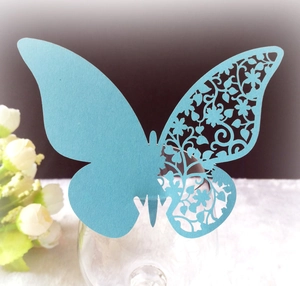 Close-up of laser-cut butterfly place card in light blue on a glass rim for weddings