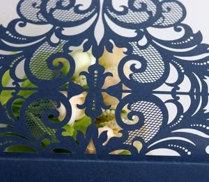 Gros plan sur les motifs floraux découpés au laser d'une invitation bleu marine haut de gamme