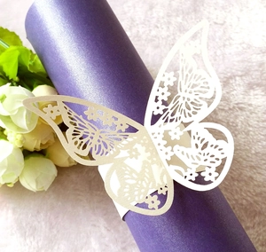 Detalle de servilletero mariposa blanco cortado por láser sobre decoración púrpura