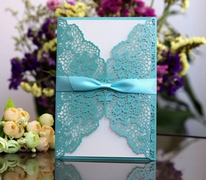Detail of laser-cut tiffany blue wedding invitation card with elegant satin bow decor