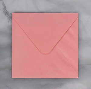 Detail view of square pink envelope with V-flap on a marble background for cards