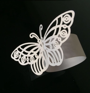 Detalle de un servilletero de mariposa en papel perlado blanco cortado con láser para bodas
