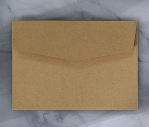 Close-up of brown kraft paper envelope with classic V-flap on marble background