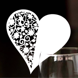 Elegant laser cut white heart shaped name card with floral patterns on wine glass