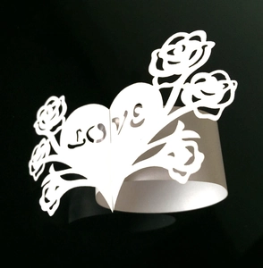 Detalle de un servilletero de papel blanco cortado con láser y el texto de LOVE