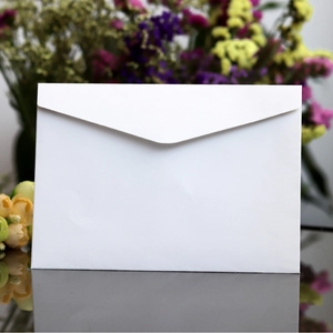 Classic white V-flap paper envelope displayed on a reflective surface with floral background