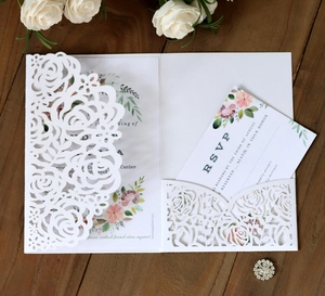 Laser-cut white rose invitation set with floral inner card and RSVP on wood background