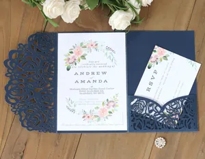 Detail of laser-cut navy floral invitation set with watercolor card on a wooden table