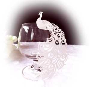 Macro detail of laser-cut white paper peacock place card for wedding glass decoration