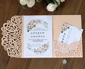 Detail of laser-cut rose hollow pocket and floral invitation cards on a wooden background
