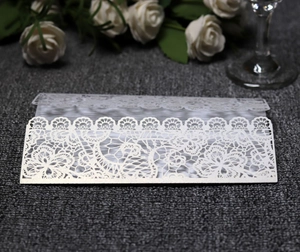 Detail of laser cut white lace wedding invitation featuring elegant floral hollow pattern
