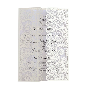 Macro view of white laser-cut lace wedding invitation with intricate floral details