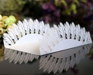 Detailed laser-cut white wedding place card with elegant hollow feather pattern and reflection