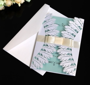Macro detail of laser-cut feather pattern wedding invitation with elegant satin ribbon bow