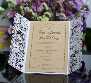 Macro view of laser-cut white lace wedding invitation with kraft paper insert