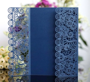 Elegant navy blue laser-cut lace wedding invitation card on a reflective dark surface