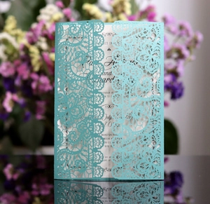 Macro detail of laser-cut lace wedding invitation in tiffany blue with elegant floral patterns