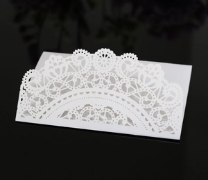 Detail einer lasergeschnittenen weißen Hochzeitskarte auf schwarzem Hintergrund