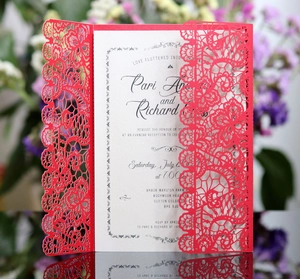Detail of red laser cut lace wedding invitation with white insert card on mirror surface