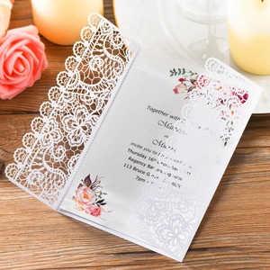 Elegant laser-cut lace wedding invitation with floral insert on a wooden table