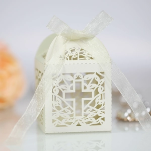 Detail of laser-cut wedding favor box with cross pattern and elegant organza ribbon