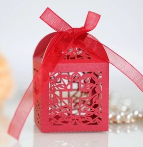 Detailed laser-cut hollow red paper wedding candy box featuring a cross and ribbon bow