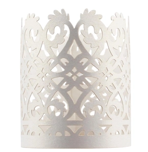 Macro detail of cream-colored laser-cut paper candle wrap with intricate floral lace patterns