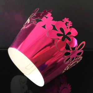 Macro detail of laser-cut sunflower pattern on metallic pink cupcake wrapper liner