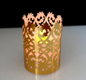Detail of laser-cut gold lace pattern on a cylindrical hollow candle shade wrap