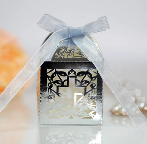 Detail of silver laser-cut cross wedding favor box with a light blue ribbon bow decoration