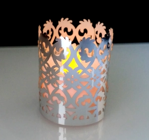 Macro view of silver hollow laser cut metal candle holder with crown pattern and warm light