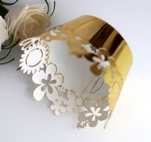 Macro shot of gold laser-cut cupcake wrappers with sunflower patterns and floral texture