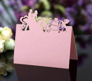 Pink laser-cut wedding place cards featuring heart silhouettes and a floral design